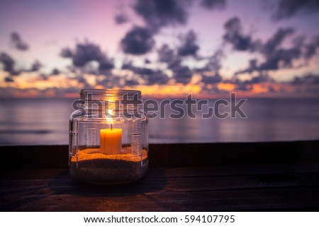 Candle lamp on table with sea and sunset background
