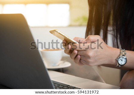 beautiful young woman use smart phone in coffee shop with laptop on table