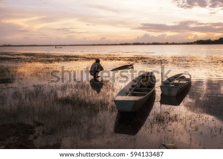 Smart photographers are shooting old boat at reservoir with sunset background.