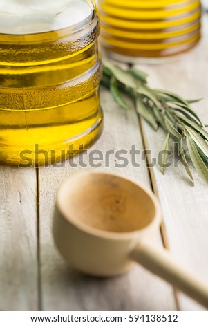 Wooden ladle and olive oil on wooden background.