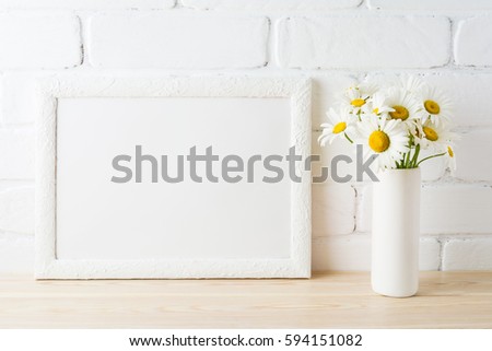 White landscape frame mockup with daisy flower in styled vase near painted brick wall. Empty frame mock up for presentation design.  Template framing for modern art.