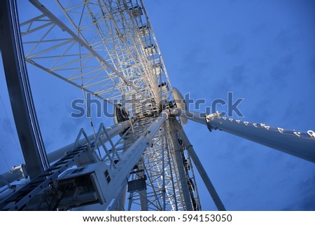 Close up of a ferris wheel with lights against a dark blue light in twilight.