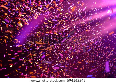 Confetti fired on air during a concert. People are happy and with hands in the air. Image ideal for backgrounds. Pink and purple are the tones of the picture