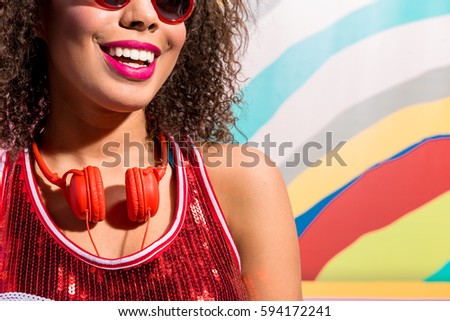 Beaming woman wearing earphones against variegated picture