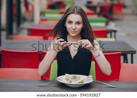 young beautiful brunette enjoys gadgets, photographs, and lunch