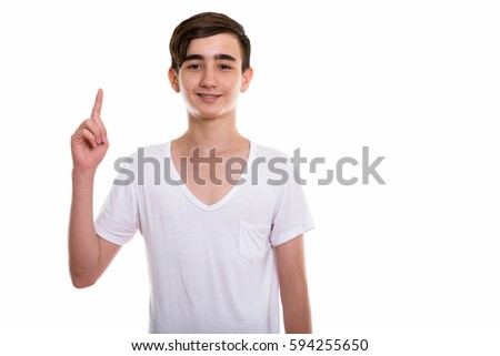 Studio shot of young happy Persian teenage boy smiling while pointing finger up