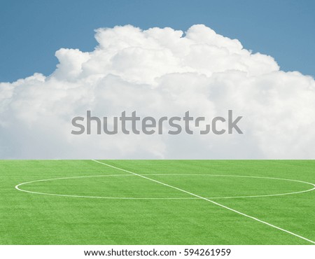 green football field against the sky with clouds