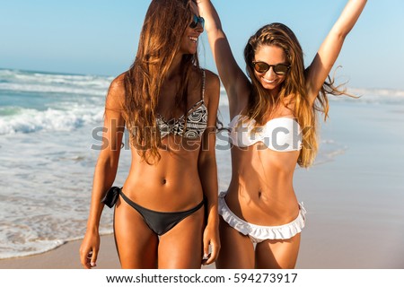 Beautiful girls walking and having fun on the beach Royalty-Free Stock Photo #594273917