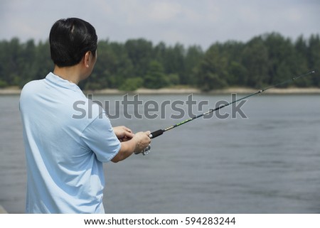 Man fishing with fishing pole, rear view