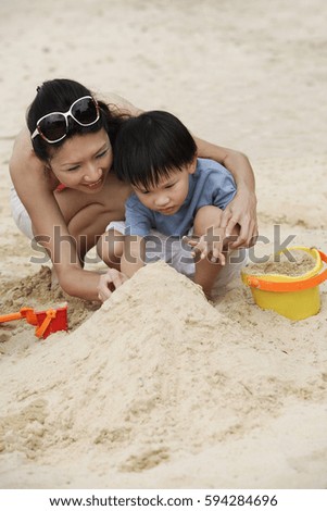 Mother and son building sand castle on beach