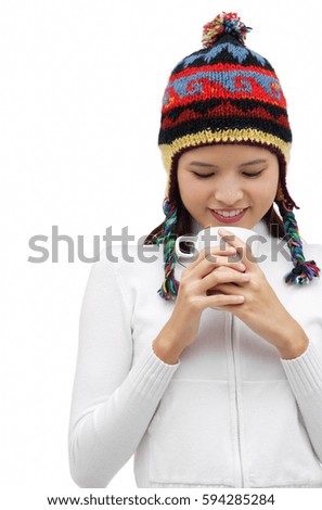 Young woman wearing winter hat and staring down at mug of hot chocolate