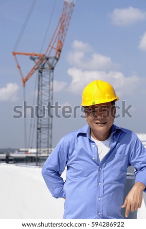 A man with a yellow helmet smiles at the camera as he works