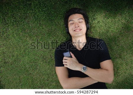A man listens to music on a mp3 player in the park Royalty-Free Stock Photo #594287294