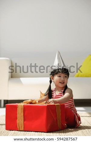 A young girl unwraps a birthday present