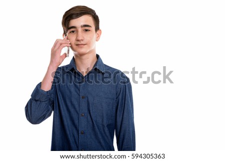 Studio shot of young handsome Persian teenage boy talking on mobile phone isolated against white background