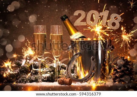 New Years Eve celebration background with pair of flutes and bottle of champagne in  bucket  and a horseshoe as lucky charm Royalty-Free Stock Photo #594316379