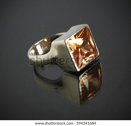 White gold or silver Jewel ring with colored gemstone closeup on black background with selective focus