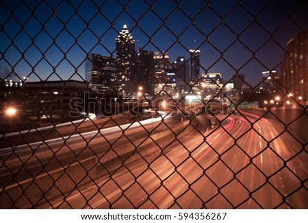 Night city skyline through the wire mesh fence. Abstract blurred cityscape background