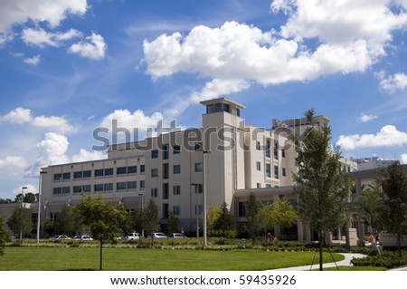 Front entrance to a hospital with palm tree landscaping and blue sky