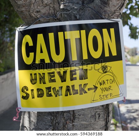 CAUTION sign attached to tree with enhanced handwritten warning.