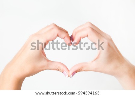 Close up of two female caucasian hands isolated on white background. Young woman forming shape of heart with her fingers. Horizontal color photography. Point of view shot