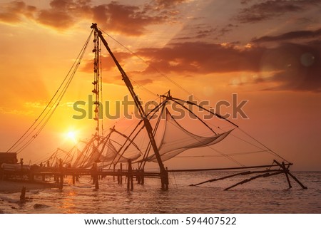 Kochi chinese fishnets on sunset. Fort Kochin, Kochi, Kerala, India. With lens flare and light leak Royalty-Free Stock Photo #594407522