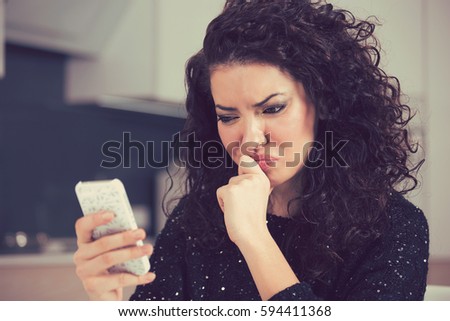 Upset confused young woman suing mobile phone reading text message  Royalty-Free Stock Photo #594411368