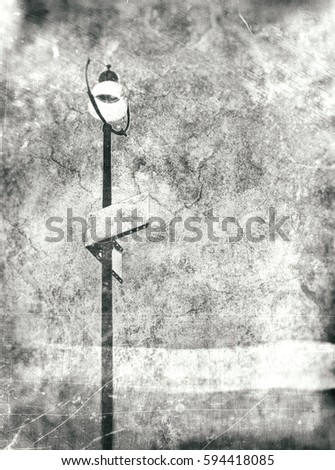 Urban street lamp with empty street sign on a stormy night textured in grey tones with cracks and blur edges as background with copy space.