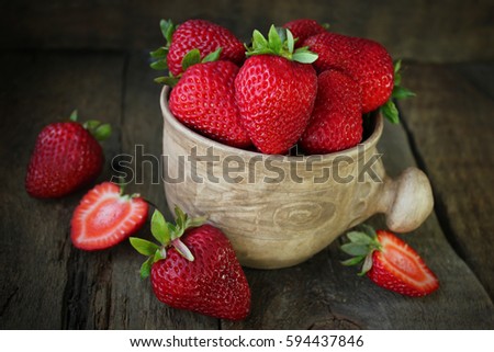 Fresh strawberries in old pottery. Rustic wood background. Selective focus.