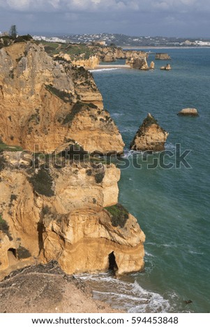 close up portrait view on wonderful seascape with stunning huge rocks cliffs with seas caves on sandy camilo beach with waves in colorful sunny blue sky with clouds, algarve, portugal