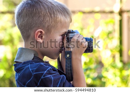 Cute little happy boy with vintage photo camera outdoors