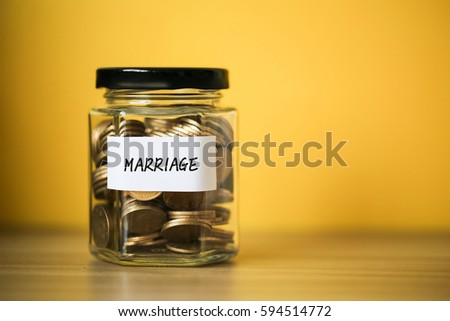 A lot coins in glass money jar with yellow background. Saving for marriage concept.