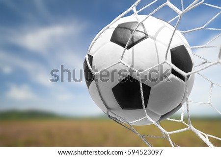soccer ball in goal net with sky background