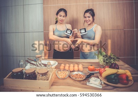 pregnant woman showing ultrasound picture and A hand-made heart symbol in the kitchen