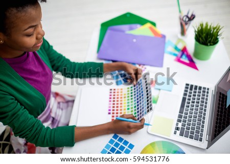 Young woman looking at color palette by workplace