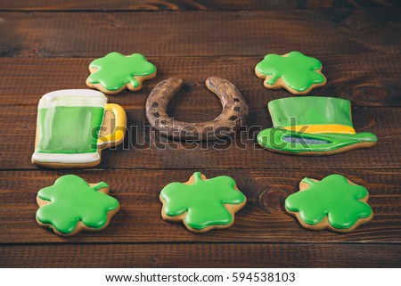 Beautiful background for St. Patrick's day with gingerbread clover, horseshoe, hat and a glass of green beer on a wooden table