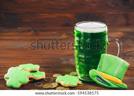Beautiful background for St. Patrick's day with a glass of green beer, gold coins and hat on wooden table. Free space.