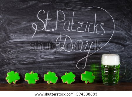 Beautiful background for St. Patrick's day with a glass of green beer and gingerbread-leaf clover on a wooden table