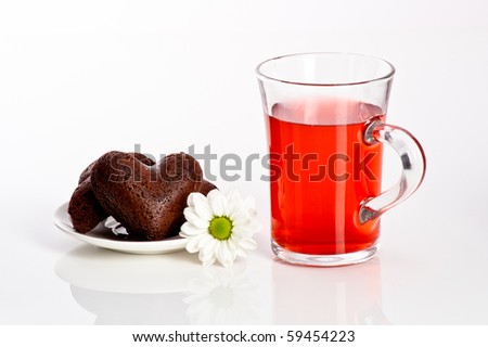 heart shaped cookie with flower on a plate and fruit tea in glass mug