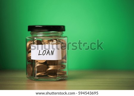 A lot coins in glass money jar with green background. Saving for loan concept.