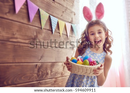 Cute little child wearing bunny ears on Easter day. Girl holding basket with painted eggs. Royalty-Free Stock Photo #594609911