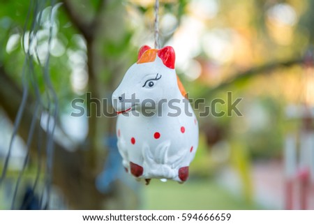 Horse clay doll hanging in the tree of garden.