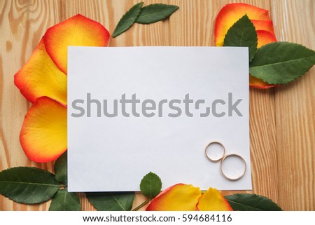 wedding rings with roses on wooden background