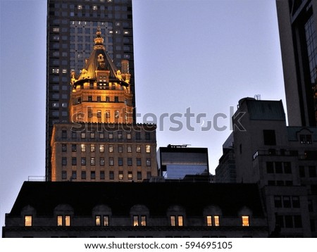 Low angle view of the setting moon crescent against the illuminated windows of a high rise commercial building in Manhattan New York