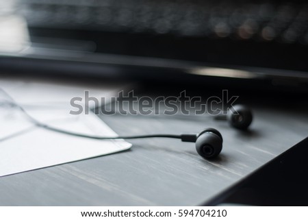 Notebook, glasses,earphone and smart phone on wood table top view with copy space