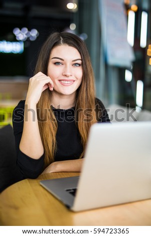 Beautiful young woman smiling and looking at camera with laptop