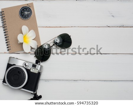 Flat lay , Sun glasses,camera,flower ,notebook,letter ,compass  with wood white background