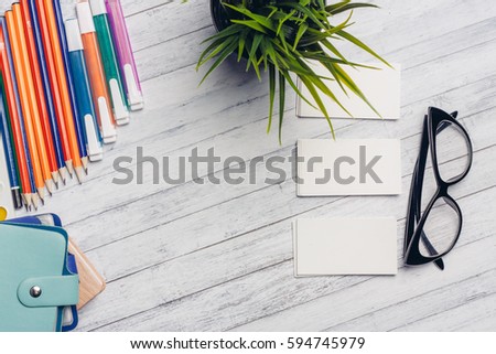 business card, notebook, sunglasses, pens, markers and scissors on the wooden background
