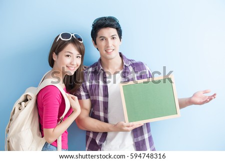 young couple show blank green chalkboard to you with blue background
