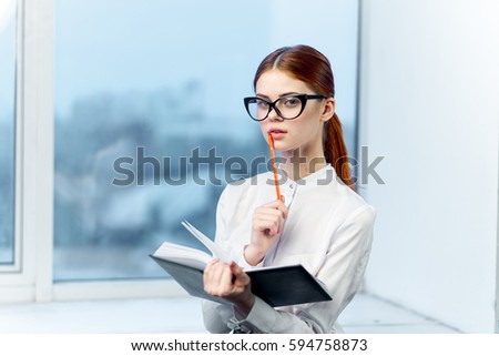 Young woman in office with notepad in hands